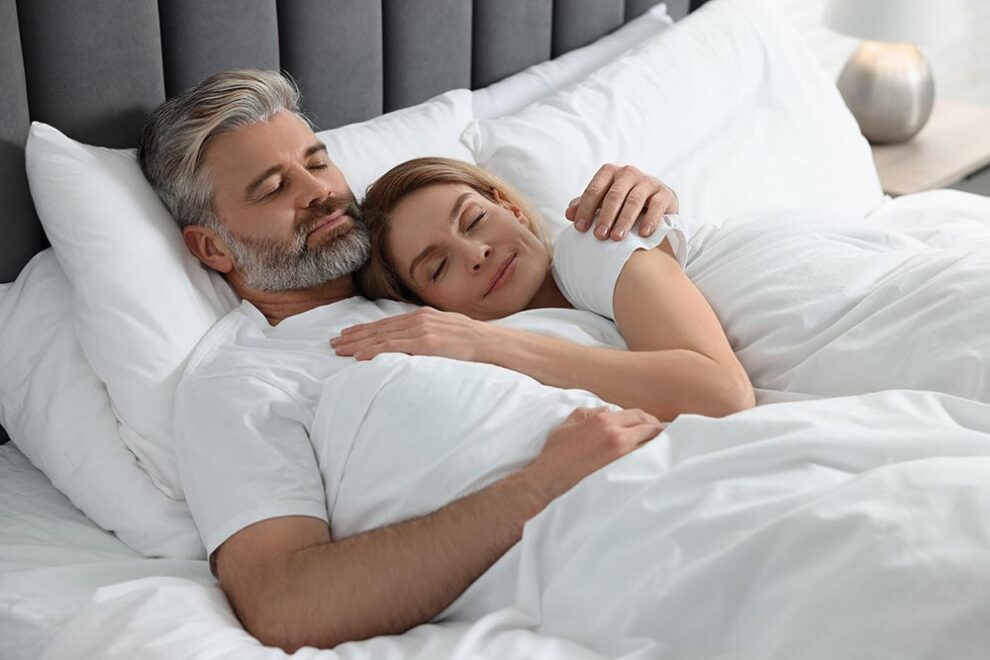 mature couple sleeping together in bed at home
